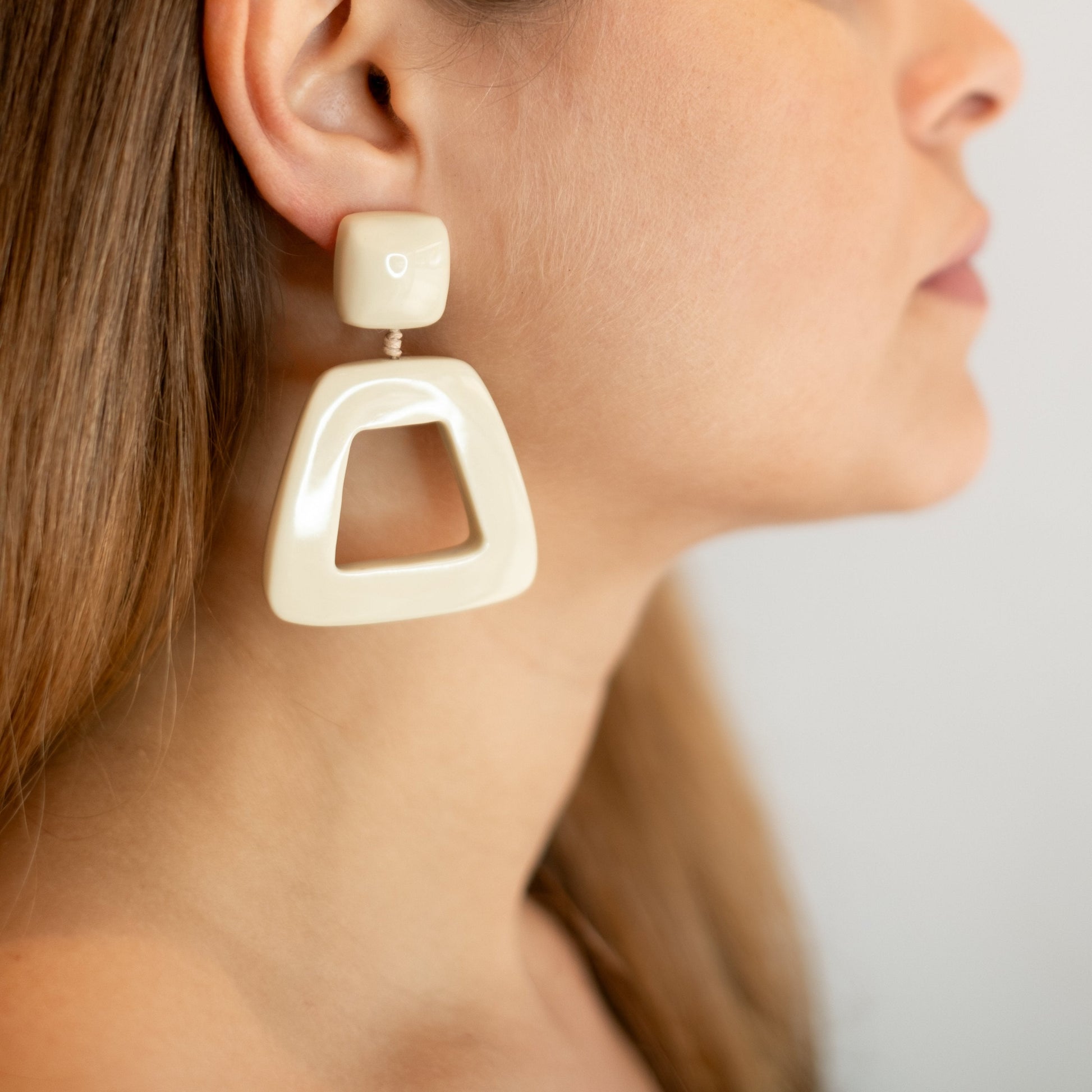 Brinco de resina geometrico, na cor marfim, modelo usando para demonstração